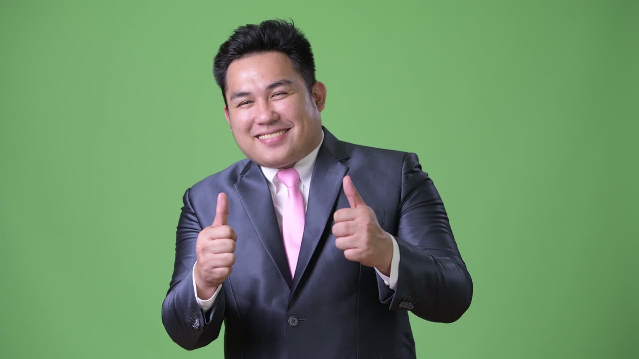 초록색 배경에 젊은 잘생긴 과체중 아시아 사업가