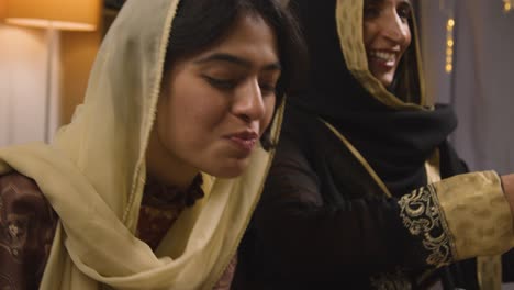 madre e hija musulmanas comiendo alrededor de una mesa en casa celebrando el eid