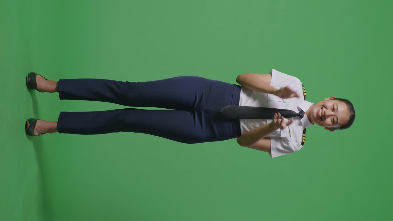 녹색 스크린 배경 스튜디오에 서 있는 동안 미소 짓고 손을 는 아시아 여성 조종사의 몸이 가득 차 있습니다.