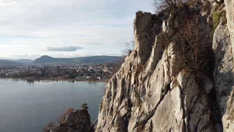 vertical motion along a cliff in front of a lake and town in the background