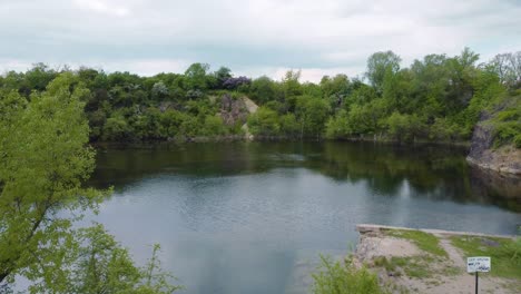 flying-towards-a-flooded-quarry-full-of-algae-with-a-forest-around