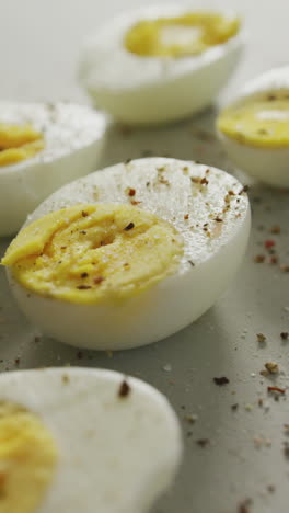 video of close up of peppered halves of hard boiled eggs on grey background