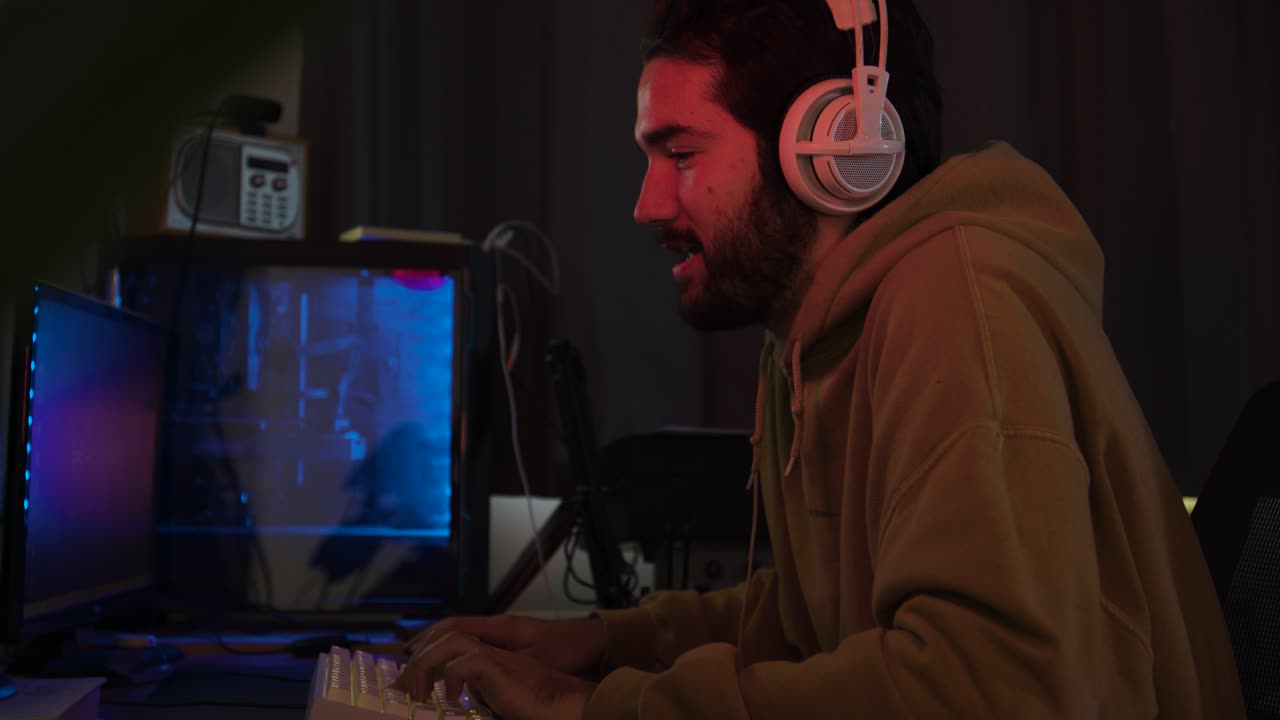 Male using PC and gaming using keyboard and mouse leaning in and smiling