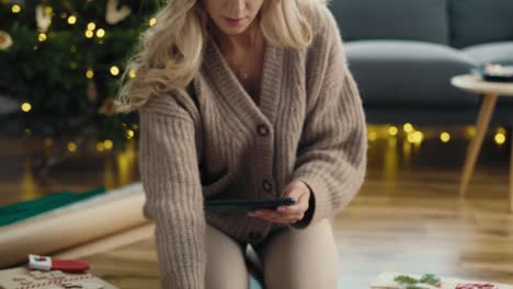 mujer tomando una foto con un teléfono inteligente de regalos de navidad envueltos.