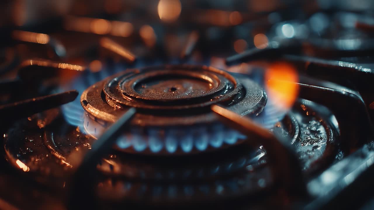 Nærbillede af en gasblusflamme med dynamiske blå og orange flammer, der fremhæver den varmeoverførende overflade og demonstrerer madlavningsintensitet og energi.