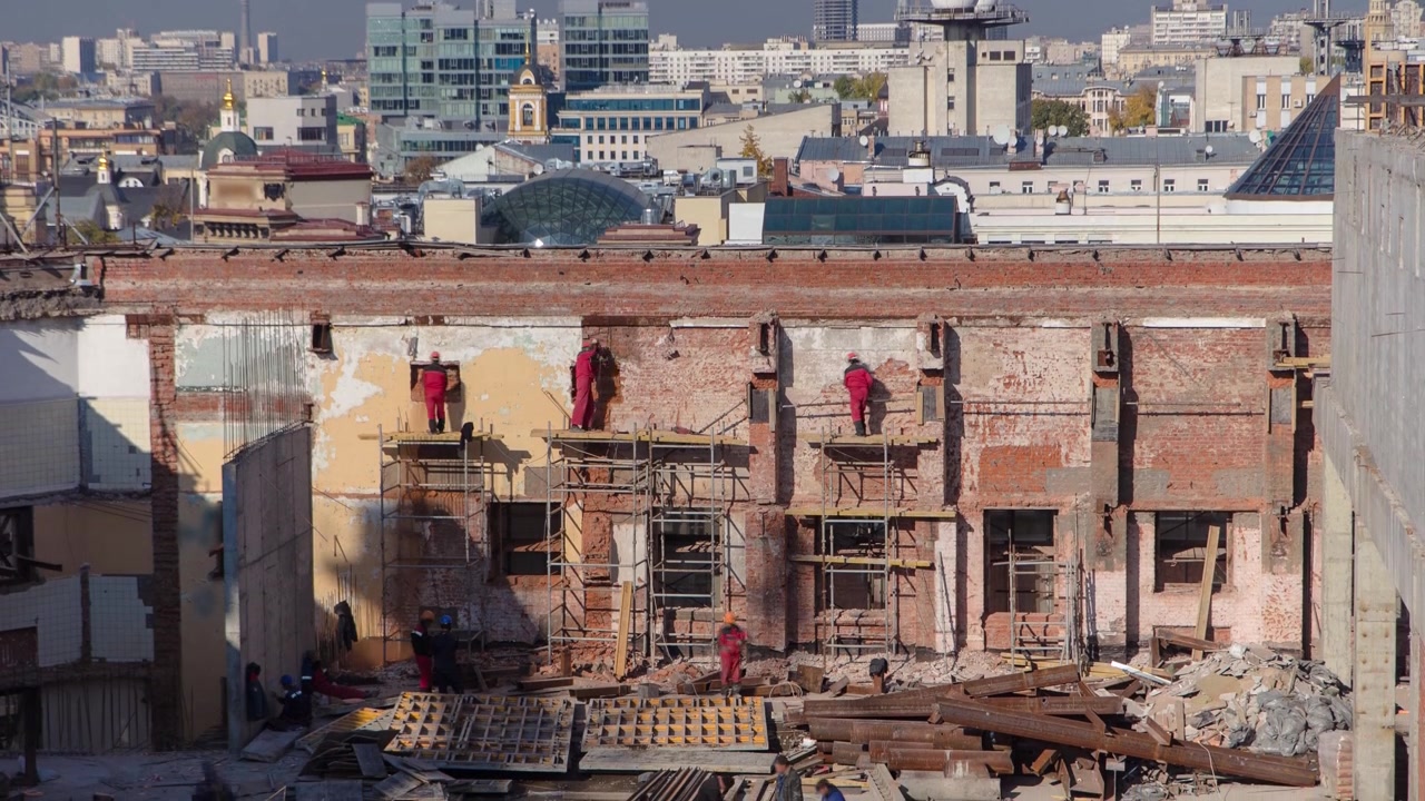 Timelapse di muratori che posano mattoni per riparare vecchi muri con rinforzo. Materiali e attrezzature edili con impalcature su un piano superiore di un edificio in costruzione.