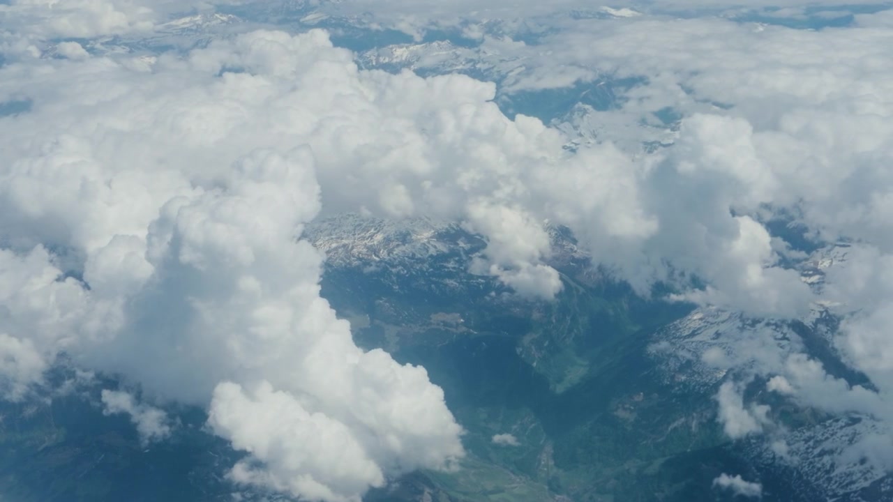 Ripresa aerea in tracciamento da aereo. Vista passeggero ad alta quota a 60fps dal finestrino, che mostra cime montuose innevate, nuvole, una cima alpina rocciosa e denso vapore bianco.