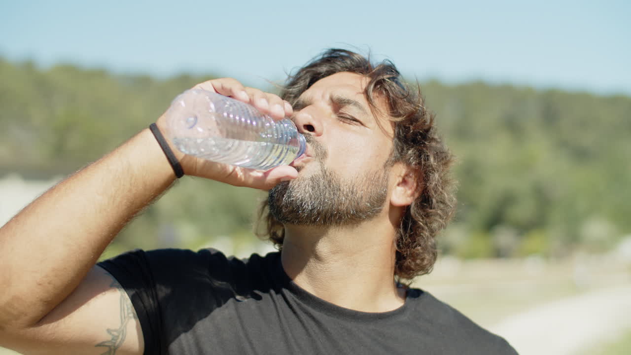 병에서 물을 마시는 심각한 스포츠맨의 클로즈업  ⁇
