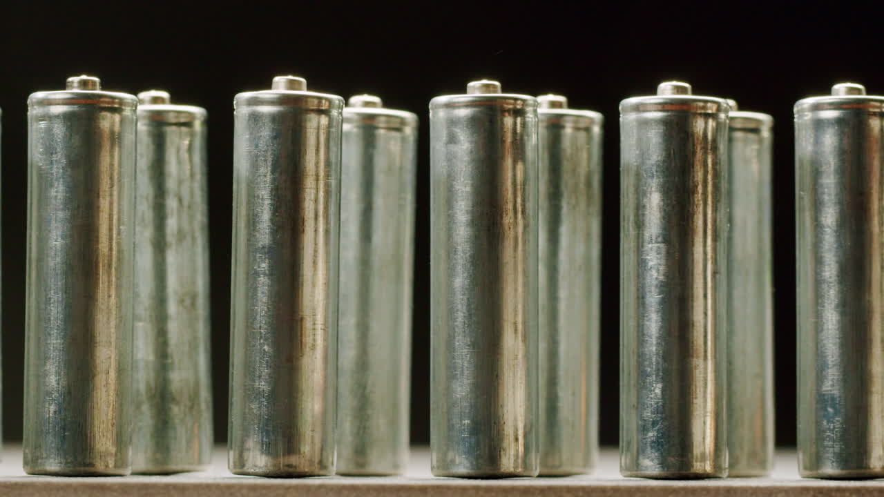 Silver batteries AA and AAA on black background close-up. Double-A battery is a standard size single cell cylindrical dry battery. Batteries are common in portable electronic devices. An AA battery is composed of a single electrochemical cell that may be either a primary battery or a rechargeable ba