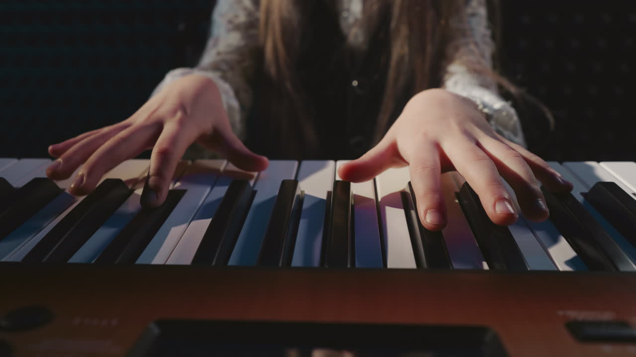 Child plays synthesizer at music school closeup. Little girl presses digital instrument keys with fingers in sound record studio. Musical art