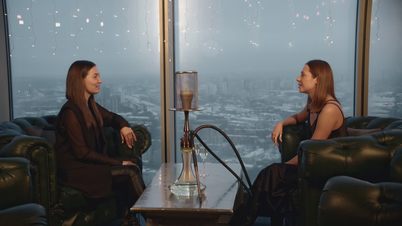 dos mujeres relajándose con narguile en un bar en la azotea