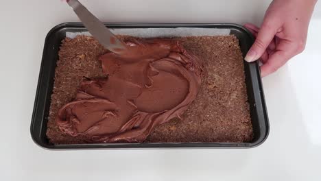 spreading chocolate icing on a slice
