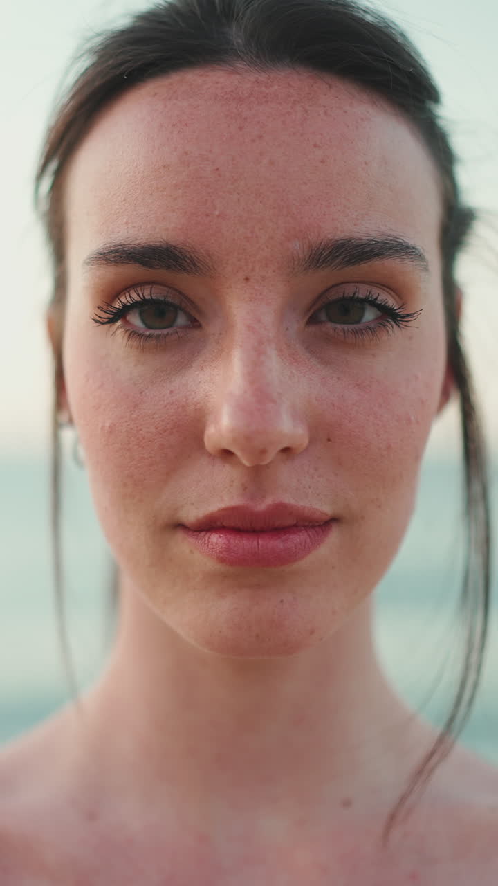 Close-up portrait of a woman with freckles and closed eyes near the sea