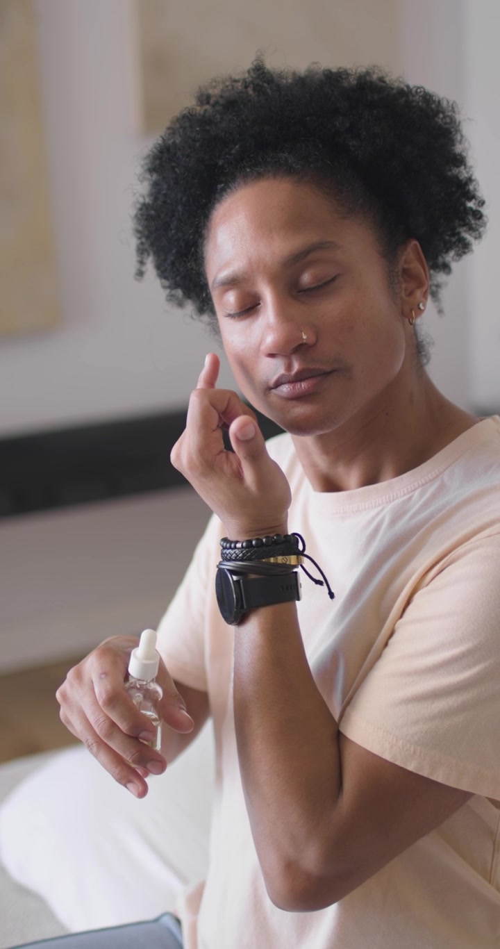 Video verticale: Uomo afroamericano che fa la skincare, testando il contorno occhi e poi applicando il siero a casa.
