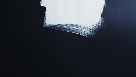 Close-up-of-white-paint-shapes-on-black-background-with-copy-space,-slow-motion