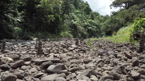 tracking shot between stacks of balancing pebbles in the rain