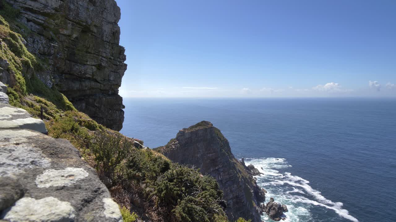 Una vista panorámica espectacular de una costa escarpada con acantilados pronunciados que se encuentran con el mar azul profundo, mostrando el poder de la naturaleza en Cape Point, Península del Cabo, Sudáfrica.