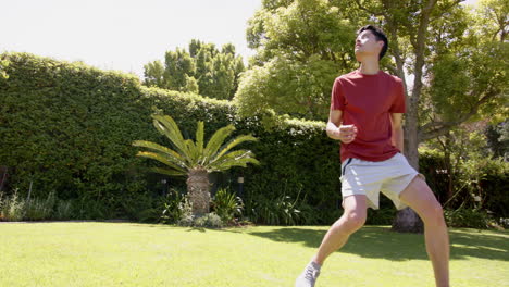 Hombre-Birracial-Enfocado-Practicando-Habilidades-Futbolísticas-En-Un-Jardín-Soleado,-Espacio-Para-Copiar,-Cámara-Lenta