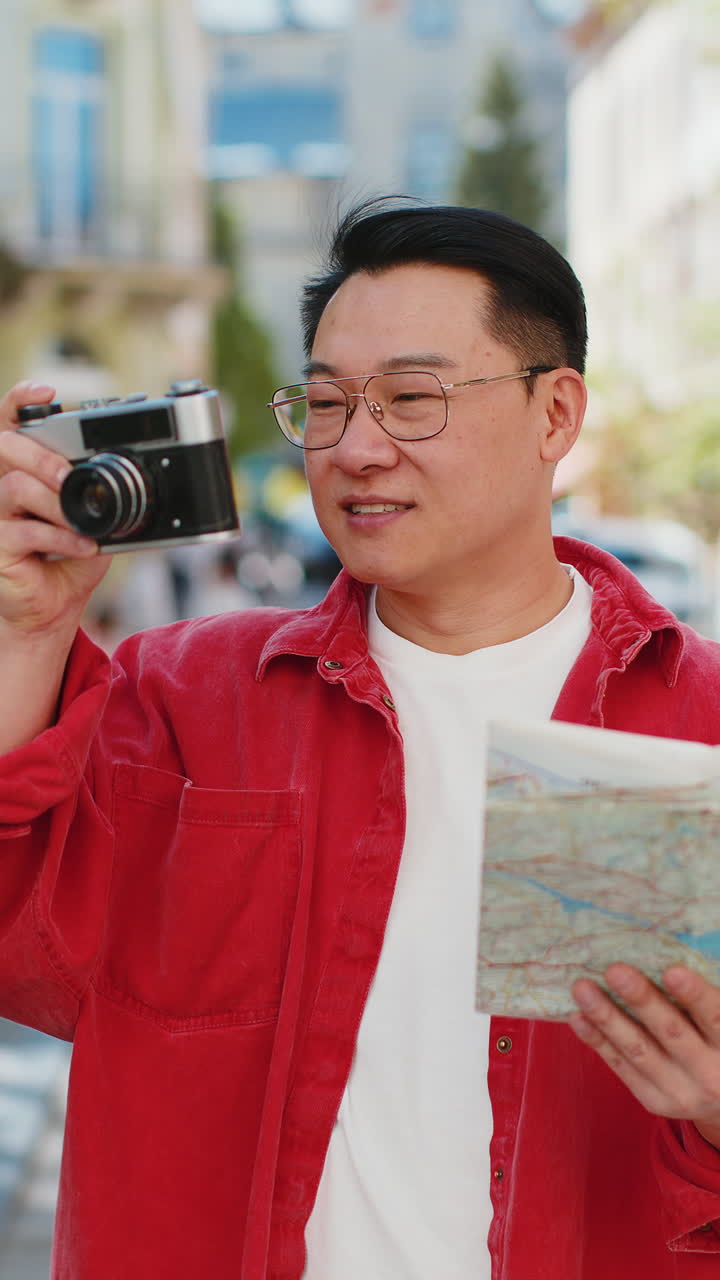 Asian man tourist traveling on weekends exploring town looking city map making photo pictures