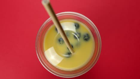 a straw is placed into a takeaway smoothie cup and which is taken away by a customer out of shot