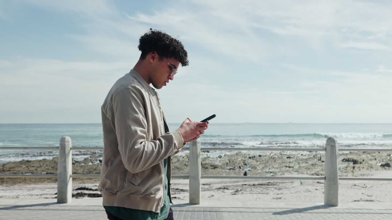 Man walking on the beach using phone