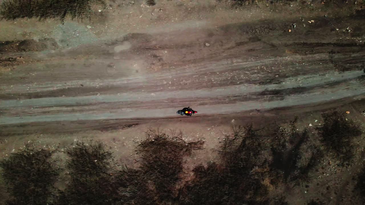 Ripresa dall'alto di una persona in moto su una strada rurale di notte.