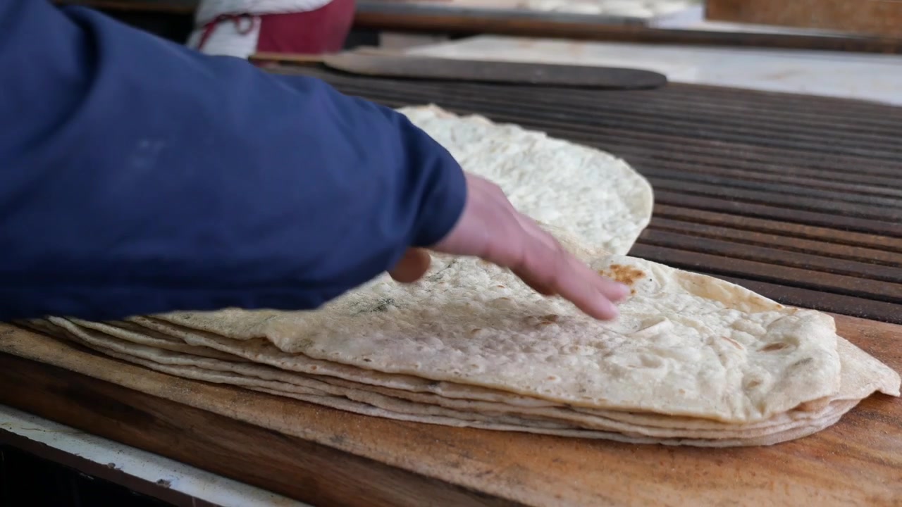 Baker Stacking Freshly Baked Lavash Flatbread in a Traditional Bakery
