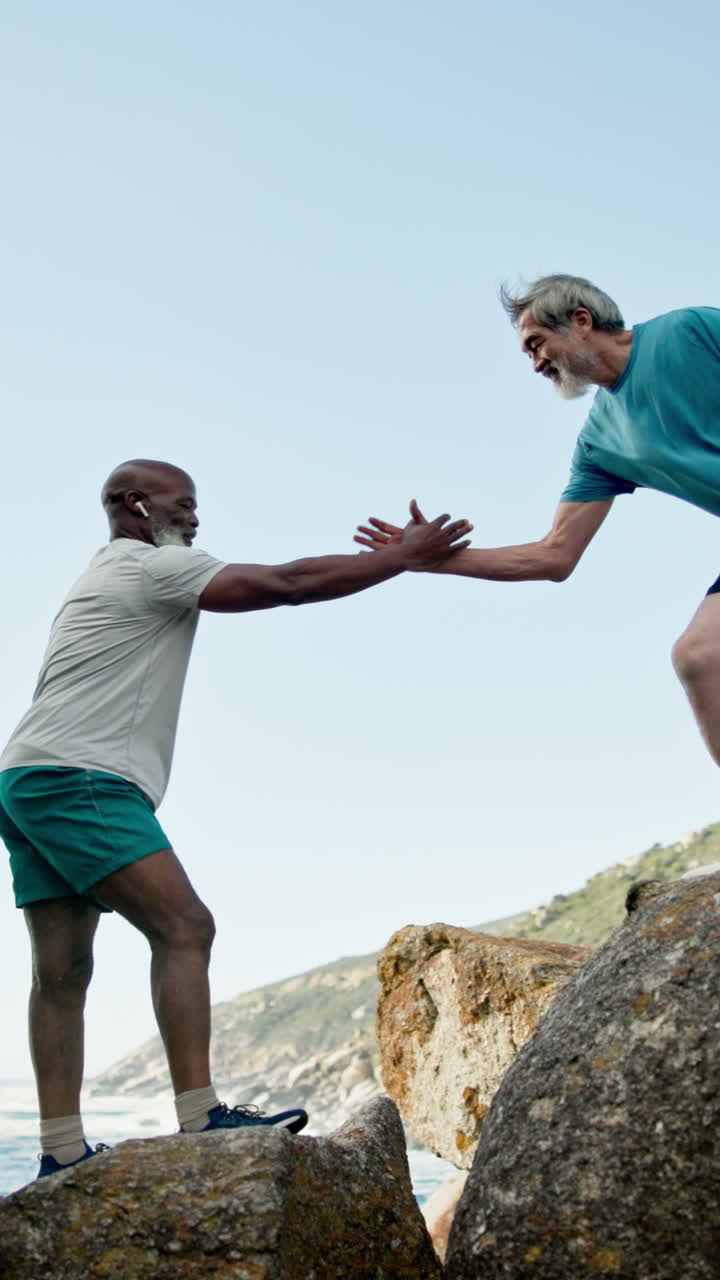 Two Senior Men Helping Each Other Climb Rocks Outdoors