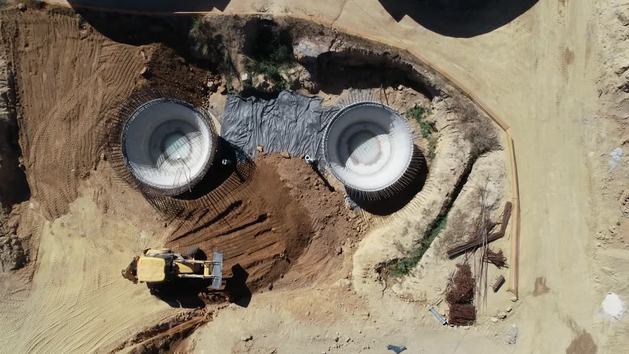 Front end loader moves soil around construction site, overhead view