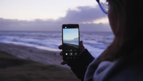 Eine-Frau-Macht-Ein-Video-Mit-Einem-Smartphone-Während-Des-Sonnenuntergangs-Am-Schönen-Strand-Von-Sylt