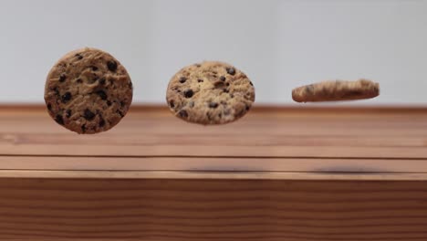 three chocolate chip cookie spinning and rolling in the air above wooden table, 4k