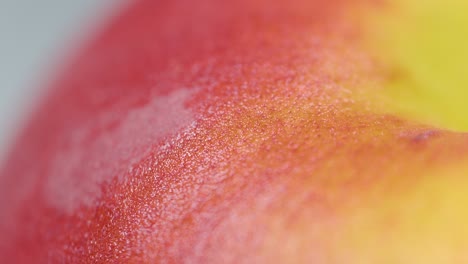 macro, dof: detailed shot of a ripe organic peach sitting on the dining table.