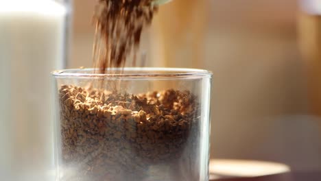 pouring instant coffee granules into a glass