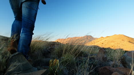 hunter with rifle over shoulder walks up on hill to look out over vast landscape