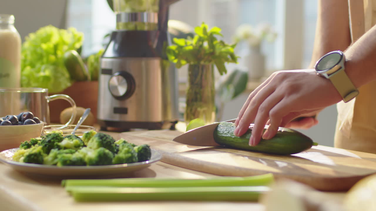 Man Cutting Fresh Cucumber at Kitchen Table