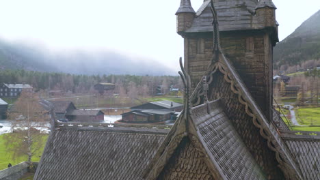 Dragon-head-and-wood-shingles,-roof-detail,-Stave-Church-Lom,-Lom,-Oppland,-Norway---aerial-drone-shot