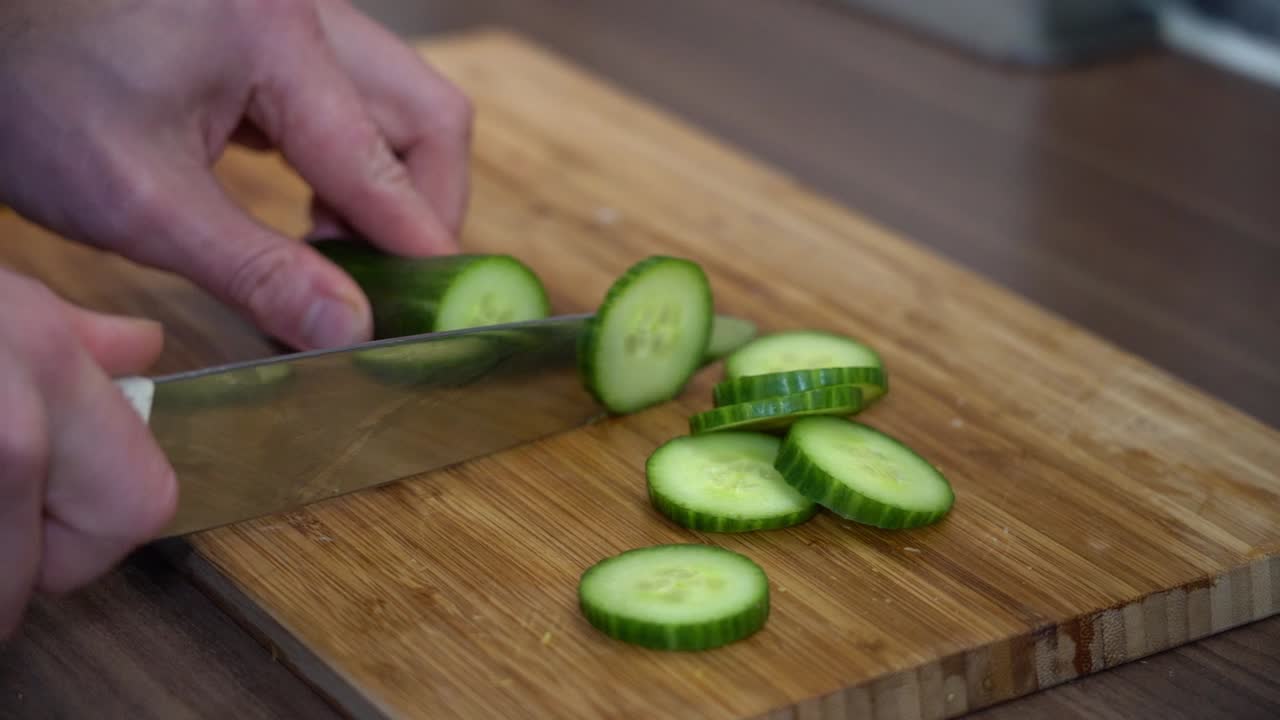 Cutting cucumber slow motion - slow motion of slices - clean green and juicy - wooden board