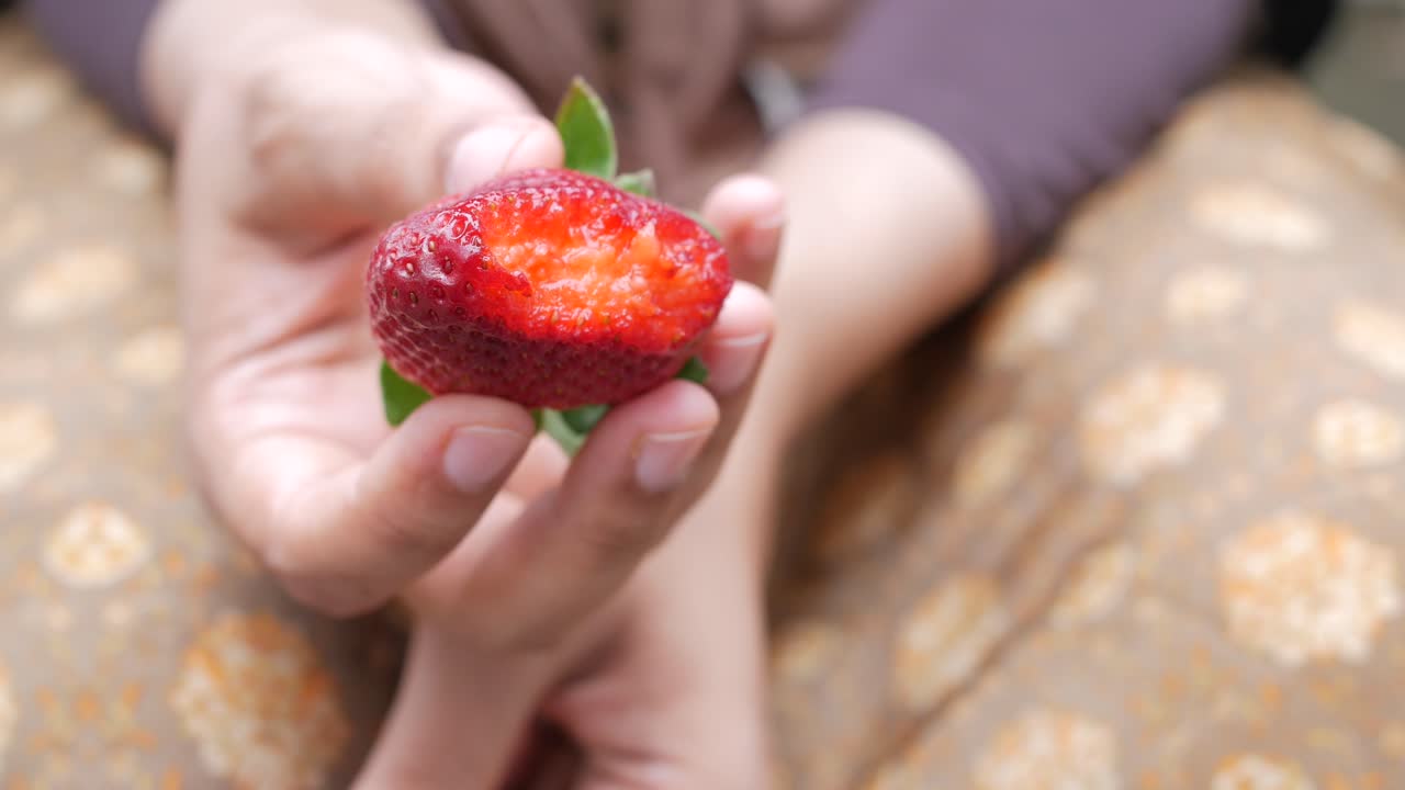 Women holding a strawberry fruit