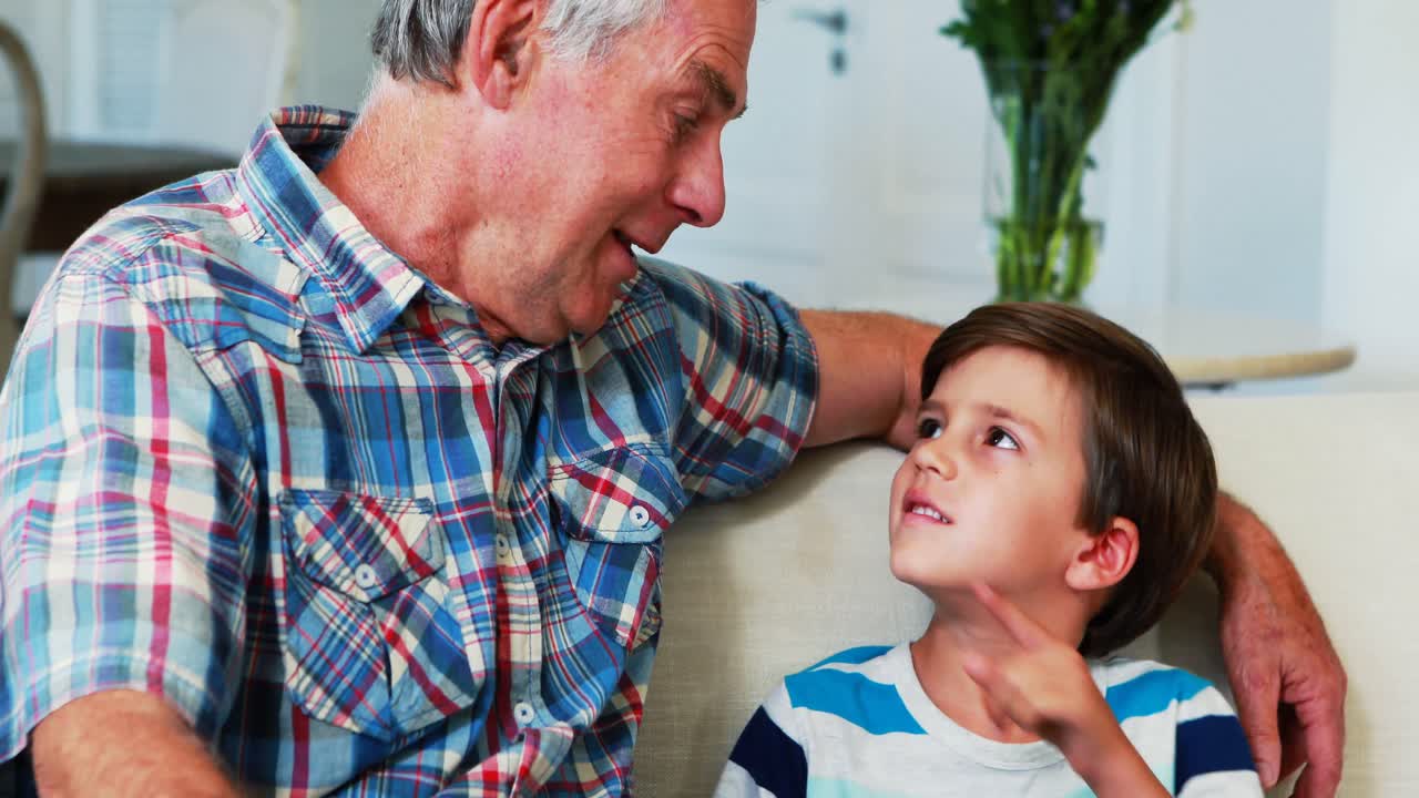 padre y hijo sonrientes usando una tableta digital en la sala de estar