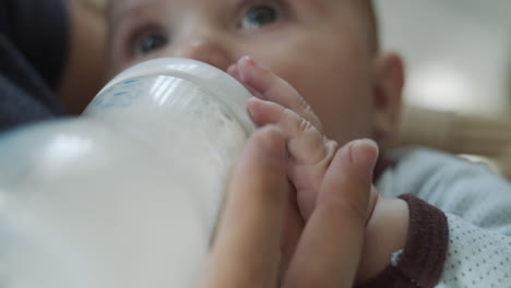 cierre las manos del bebé sosteniendo un biberón con nutrición para bebés durante la alimentación