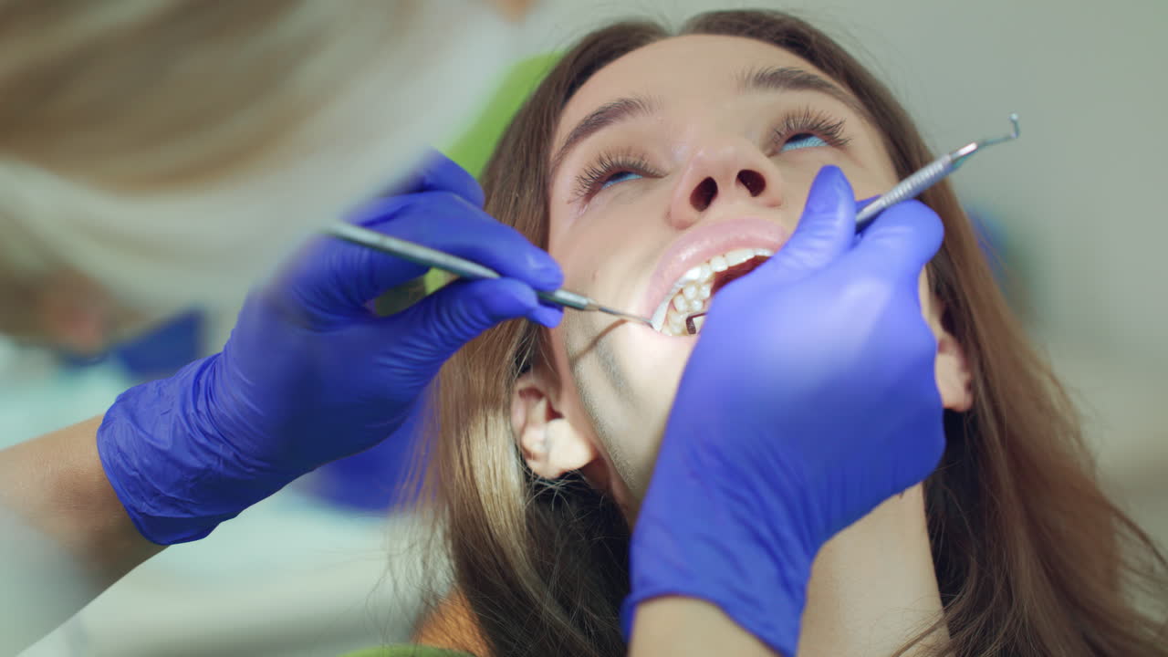 Woman face with open mouth. Dentist hands examining patient teeth