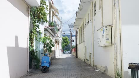 narrow alleyway in a greek town with a blue scooter