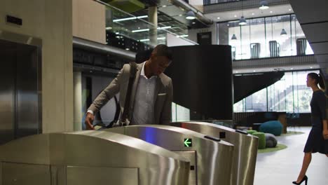 African-american-businessman-arriving-in-office-using-smartphone-at-security-gates