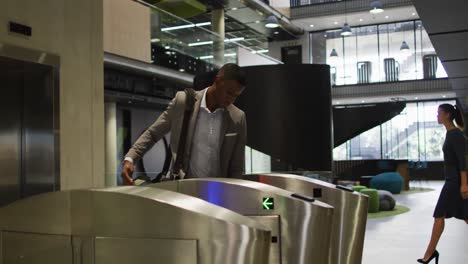 african american businessman arriving in office using smartphone at security gates