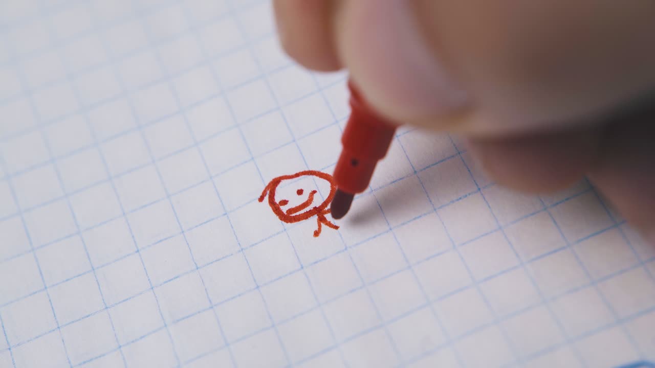 un joven dibuja a un humano gracioso usando un marcador rojo en el papel