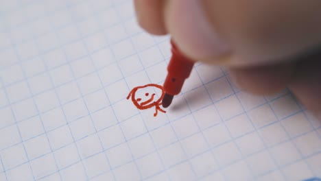 young man draws funny human using red marker on paper