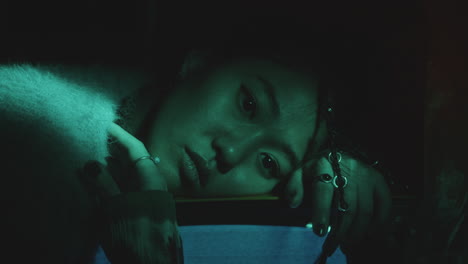 portrait of gloomy asian girl leaning on vintage tv among plastic wrap curtains