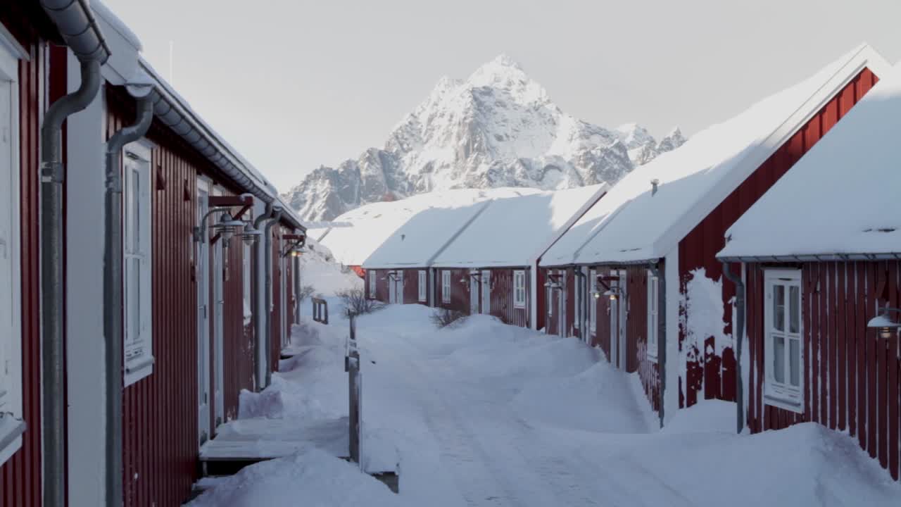 Fixed shot of a beautiful landscape with red bungalows in Svolvar, Lofoten Islands on a sunny and snowy day