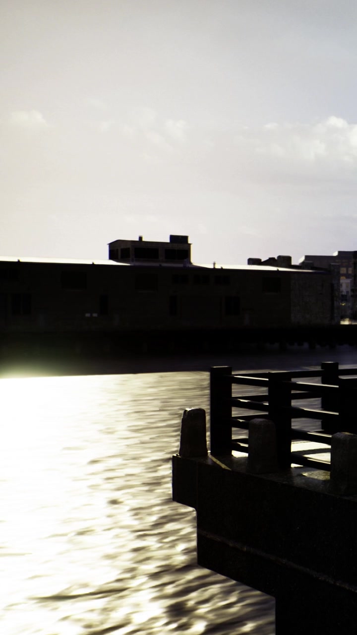 Sunset view over water with buildings in the background near the pier