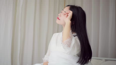 피자마를 입고 일어나는 아름다운 소녀의 실제, 큰 창문 근처에 앉아있는 침대에서 깨어나는, 완전히 휴식을 취하고, 아침에 신선한 공기와 빛을 얻기 위해 커튼을 펴는.